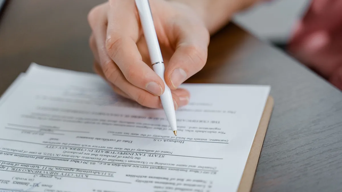 Close-up of hands signing a board resolution document