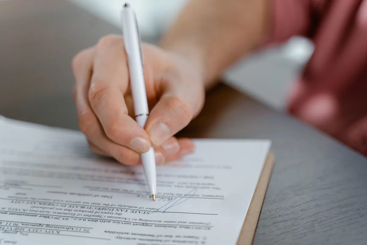 Signing a printed company document at a desk