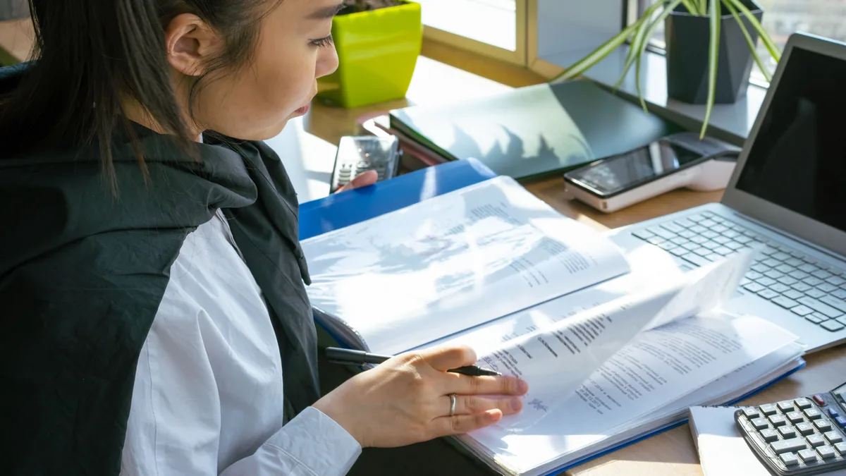 A desk with a laptop showing a document under review, representing the substance checks behind a VAT-registration risk review