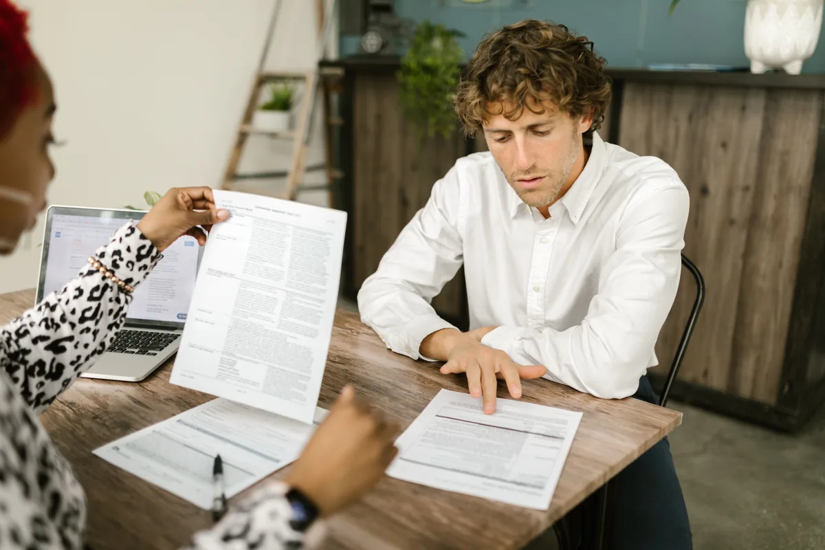 Two professionals reviewing paperwork during a due-diligence check
